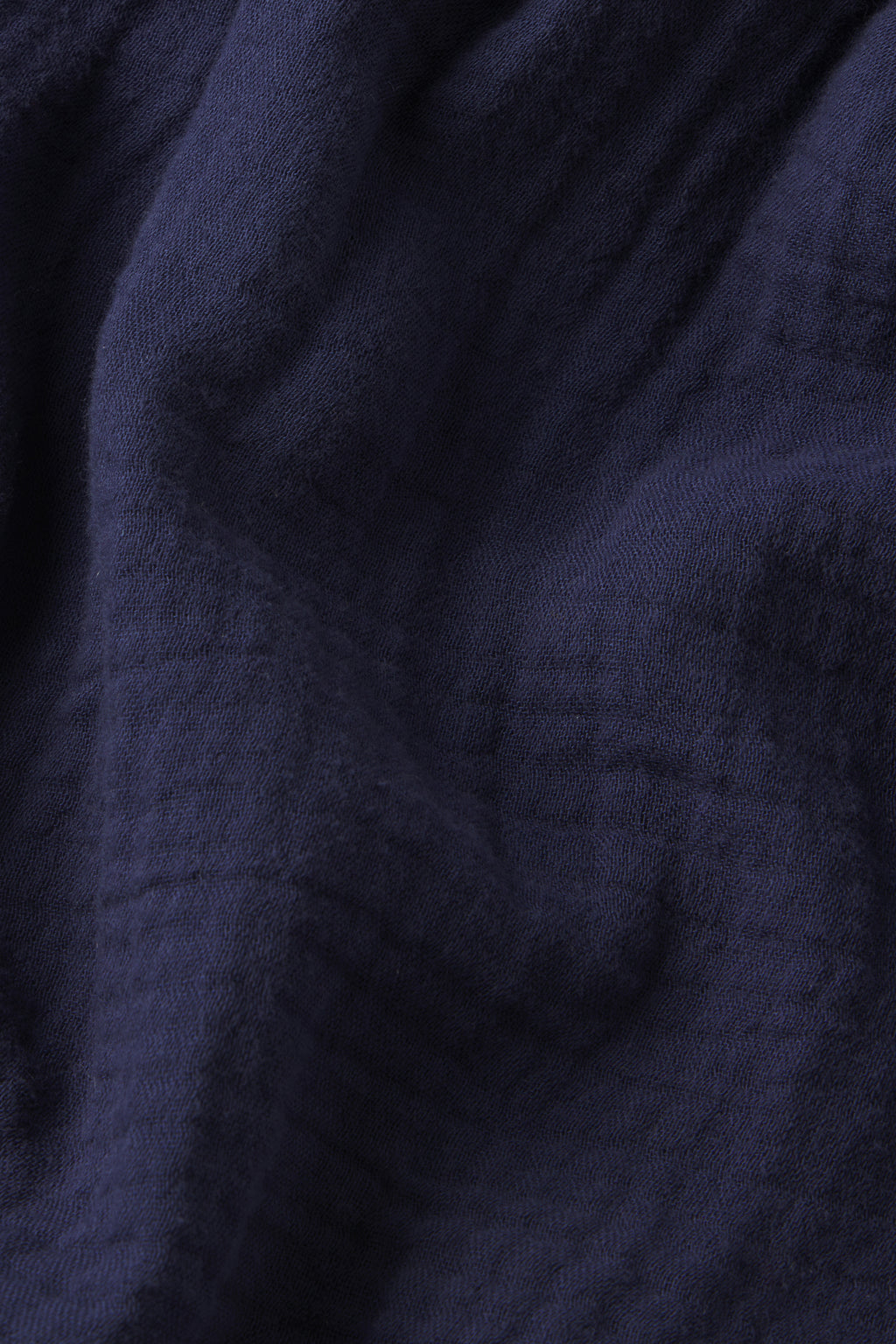 Close-up of the Hamptons Pants Set in English Navy, showing dark blue gauze fabric with gentle folds and subtle checkered patterns. The surface is soft, slightly wrinkled, and perfect for hot sleepers.