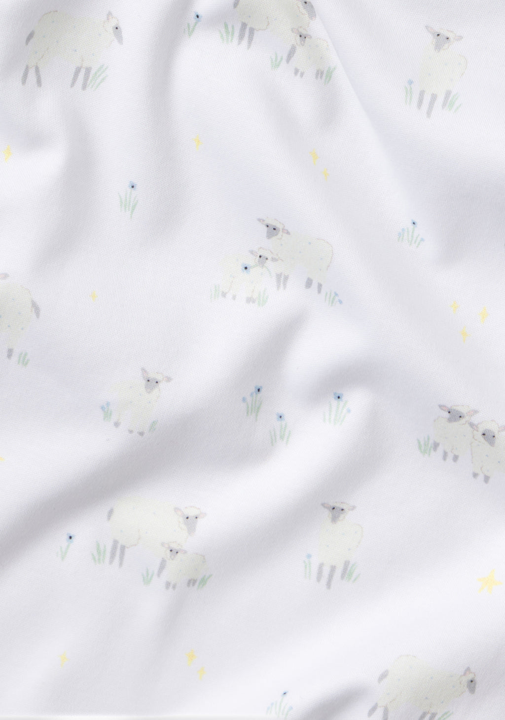 The Baby Long-Long Set in Sleepy Sheep features soft white Pima cotton with a wrinkled texture, printed with small Sleepy Sheep, yellow stars, green grass sprigs, and blue flowers.