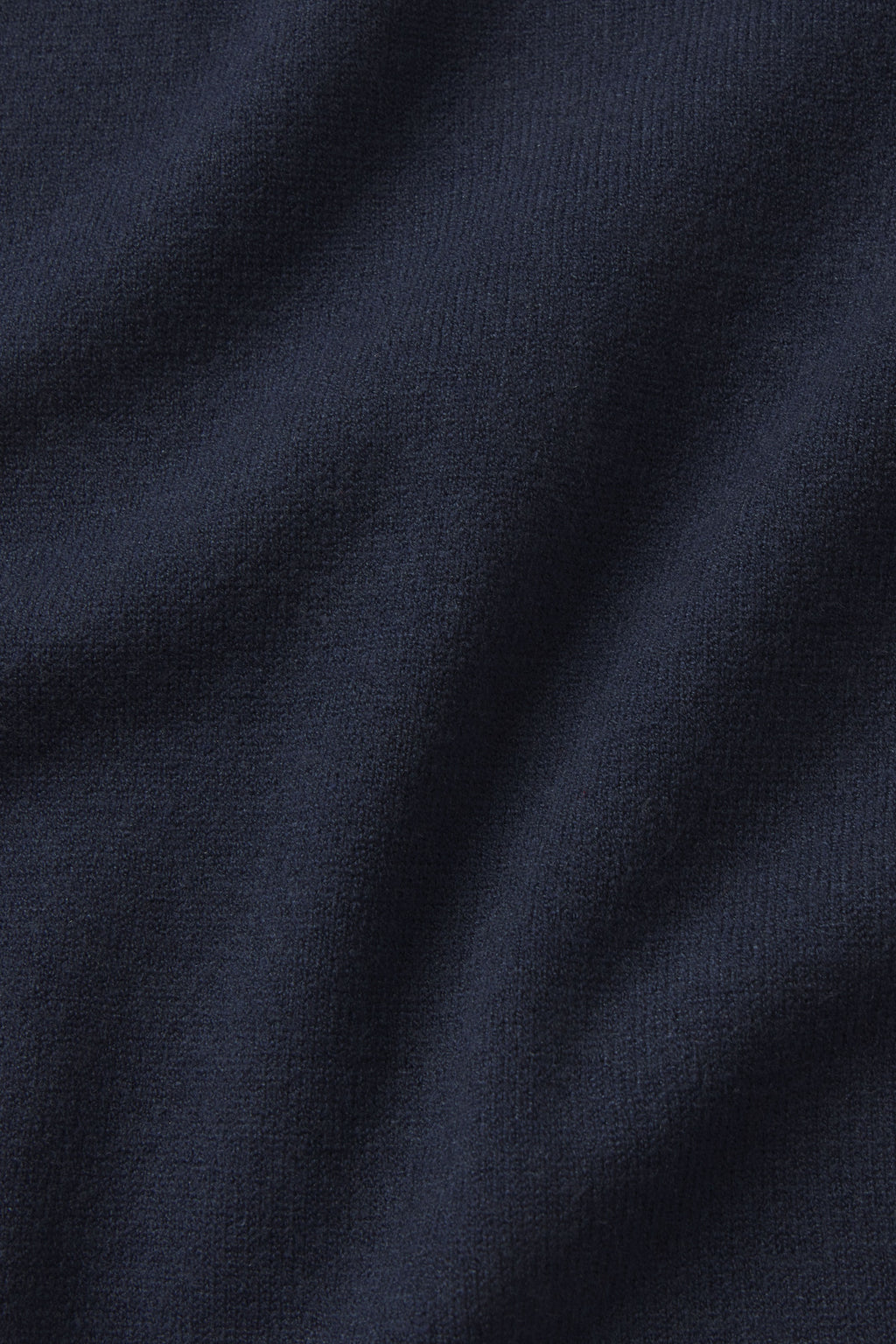 Close-up of deep navy fabric from the Vesper Crew Neck Set, highlighting its soft texture and smooth, elegant folds that create subtle shadows.