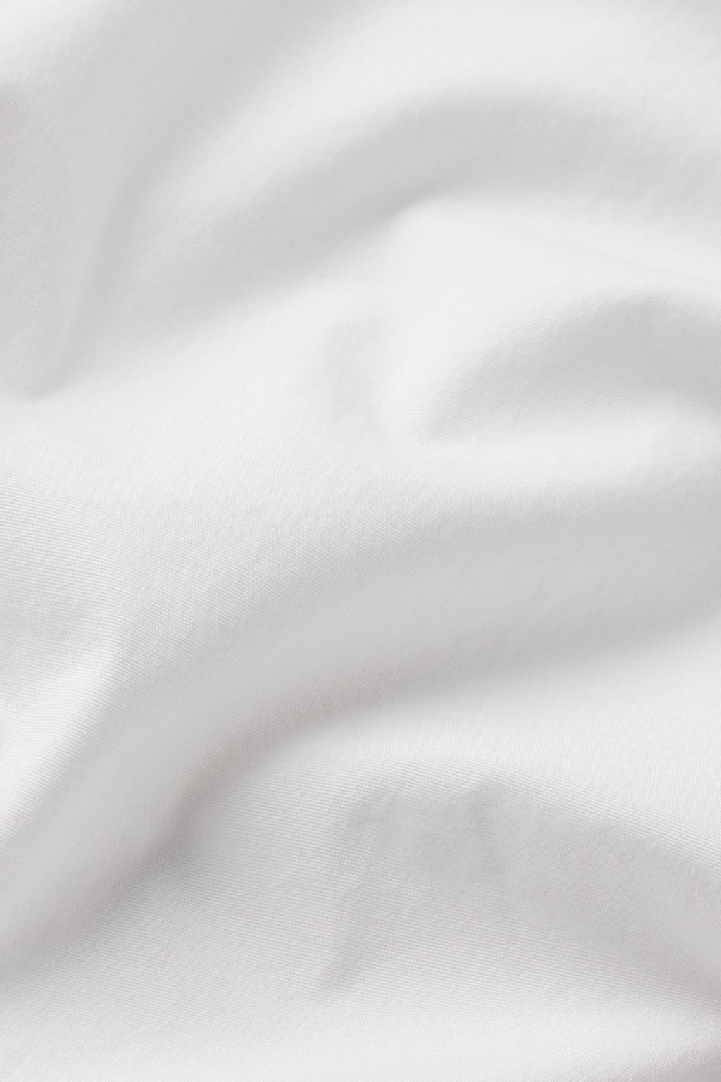 A close-up view of the Terrace Skirt Set in White, showcasing its wrinkle-resistant cotton poplin fabric with soft folds and gentle shadows.