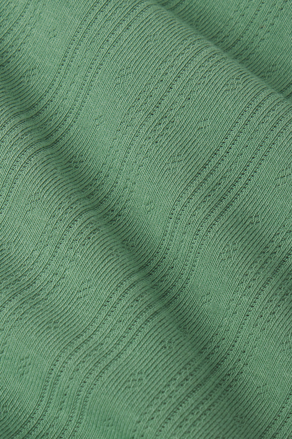 Sage green pointelle knit fabric with vertical ribbed texture and openwork pattern detail.