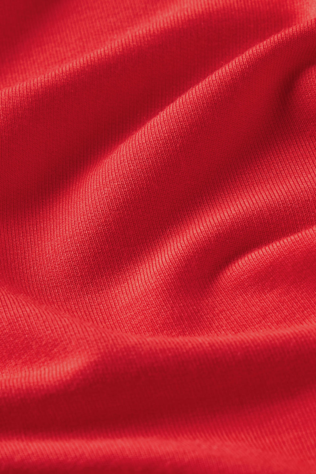 Close-up of bright red fabric in the Relax Short Sleeve Shorts Set in Tart, showing ribbed texture and gentle folds that create soft shadows and highlights across the surface.
