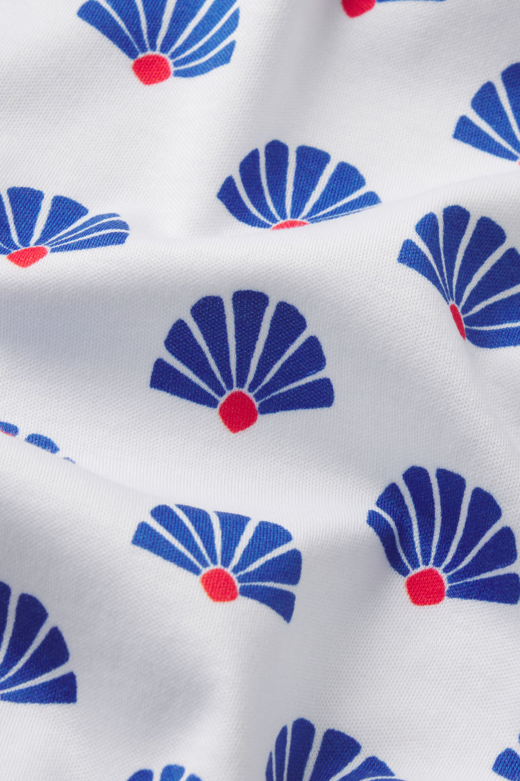 White fabric with repeating blue fan shapes and red circular centers throughout.