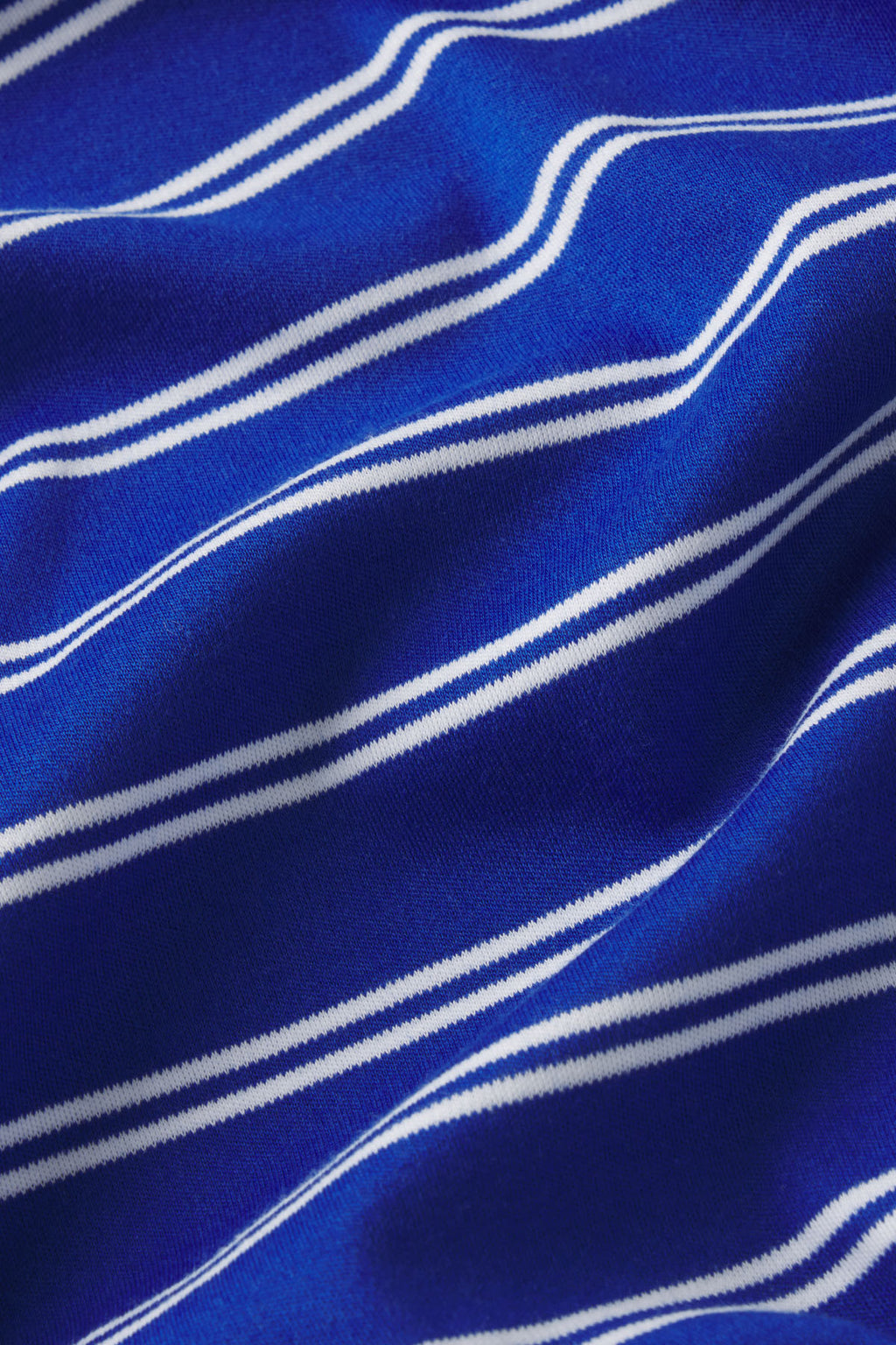 Blue fabric with white wavy stripes in a diagonal pattern.