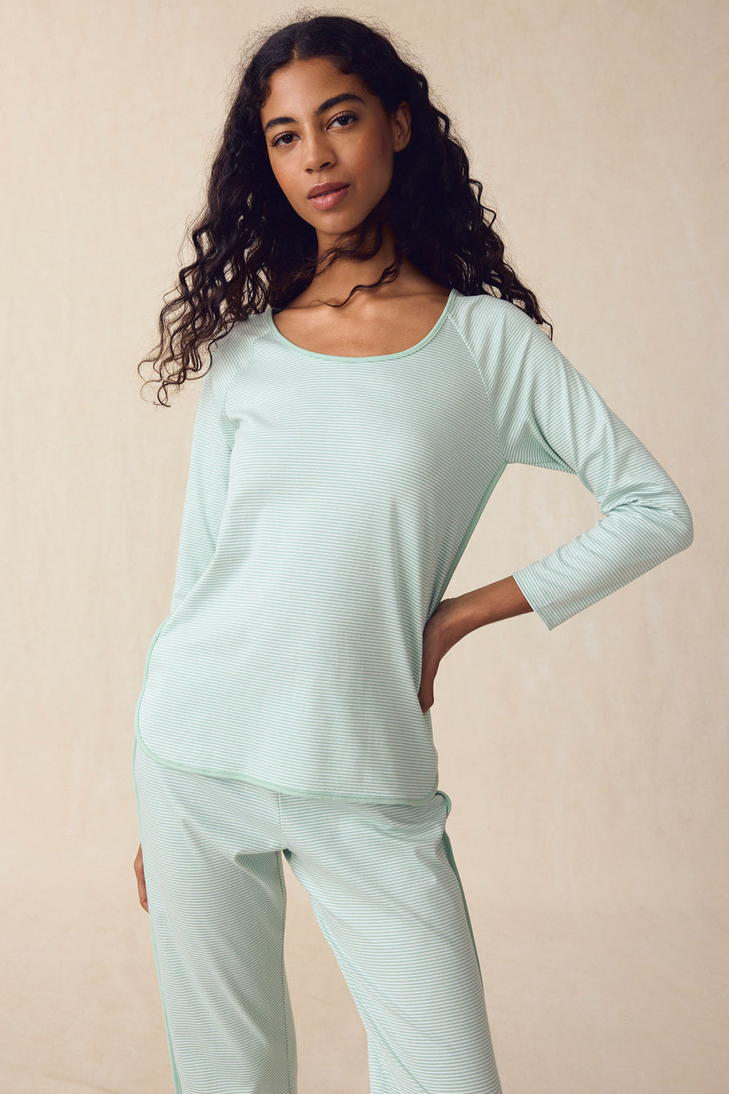 A woman wears the Pima Long-Long Set in Parisian Green—three-quarter sleeve top and matching elastic waistband pants—standing with one hand on her hip against a neutral background.