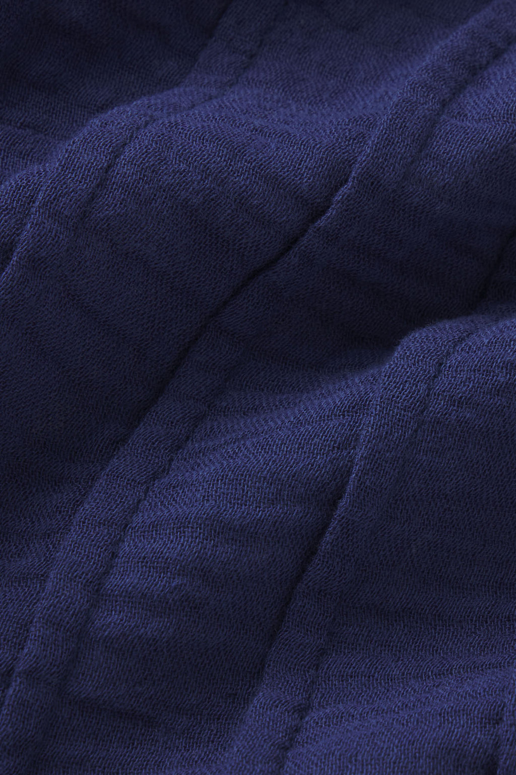 Close-up of Monaco Nightgown in Blue Depths Gauze shows dark blue cotton fabric with visible stitching and soft, slightly raised ridges for a quilted, padded look.