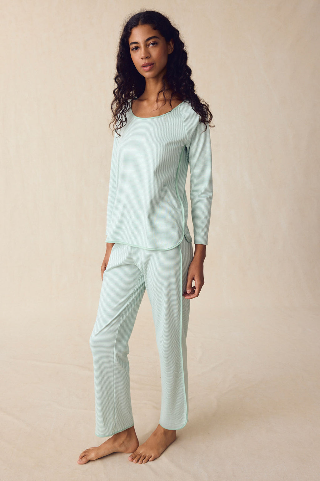 A woman stands on a light background, calmly looking at the camera in the Pima Long-Long Set in Parisian Green, featuring a matching pajama set with an elastic waistband and long sleeves.