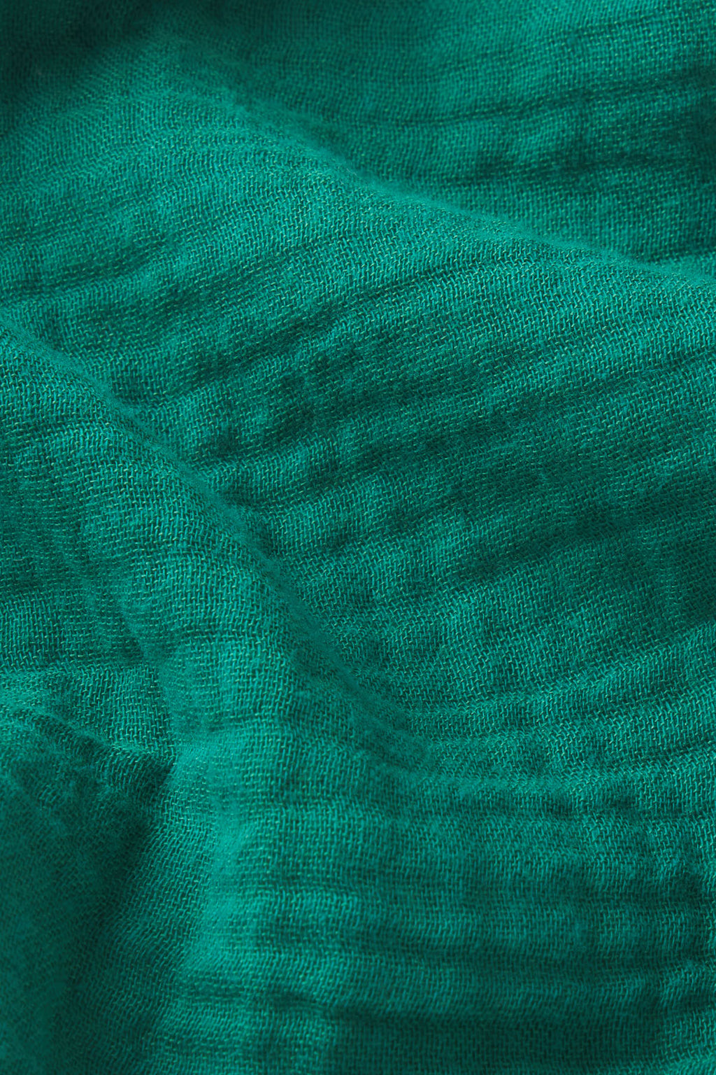 Close-up of the Monaco Nightgown in Opulent Gauze shows jewel-tone green fabric with a visible woven pattern and gentle folds, creating a subtly rippled texture.