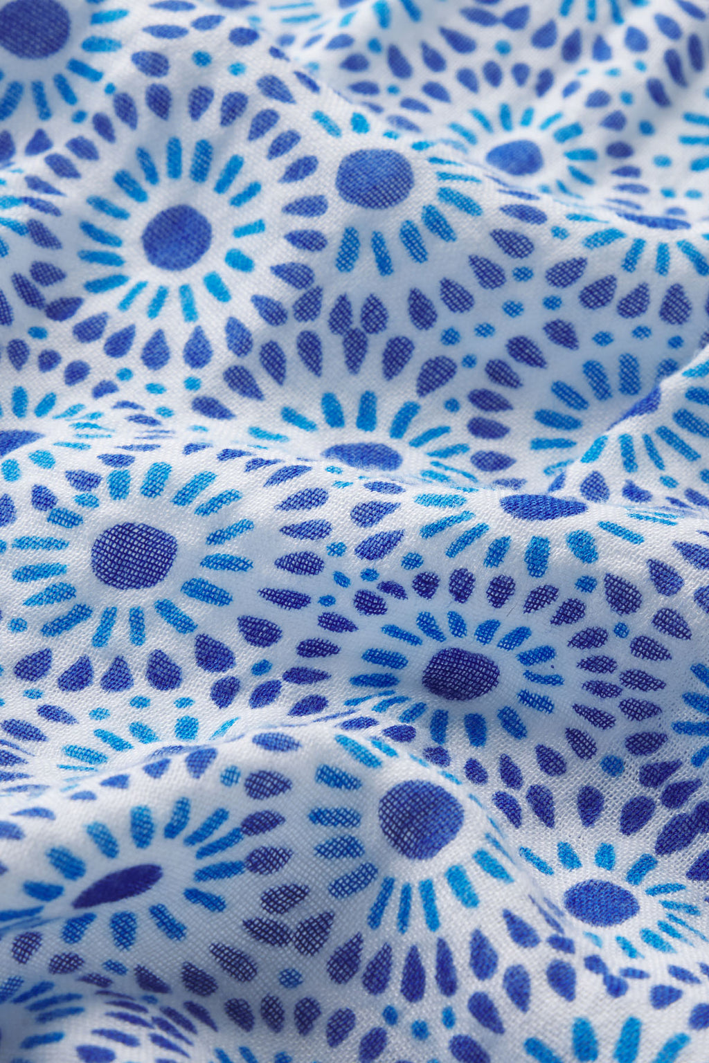 A close-up of the Hamptons Pants Set in Lapis Dot Gauze highlights white fabric with blue and dark blue circular, floral dots. The soft, textured gauze brings comfort—ideal for hot sleepers.