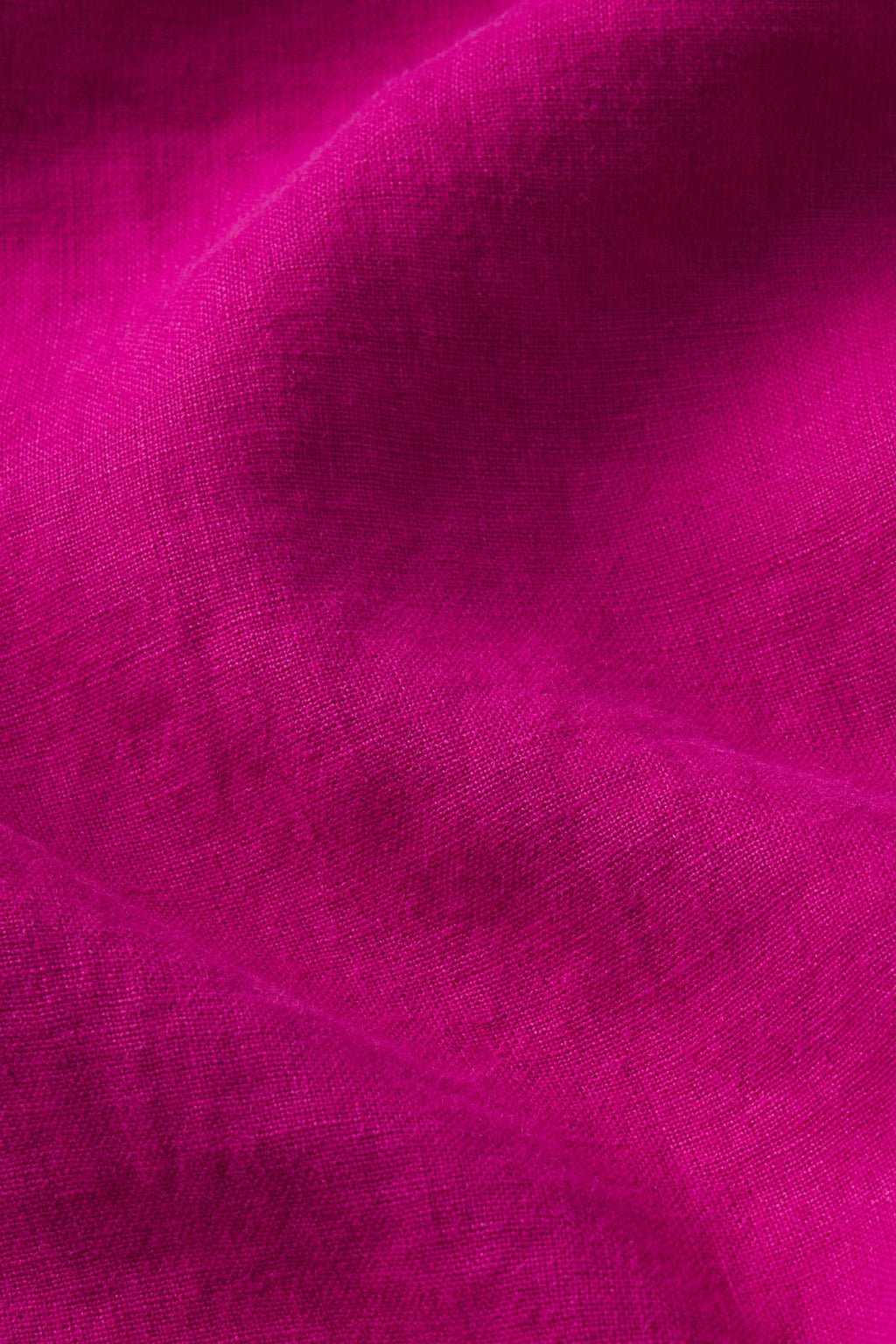 Close-up of the Flute Skirt Set in Fuchsia reveals vibrant magenta linen fabric, showcasing a distinctive woven texture and gentle, flowing folds for a soft, smooth look.
