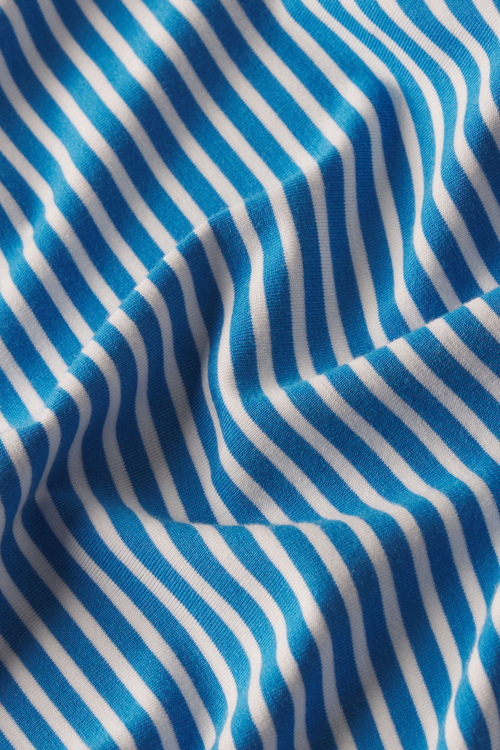 Blue, white, and gray vertical pencil stripe pattern on draped fabric.