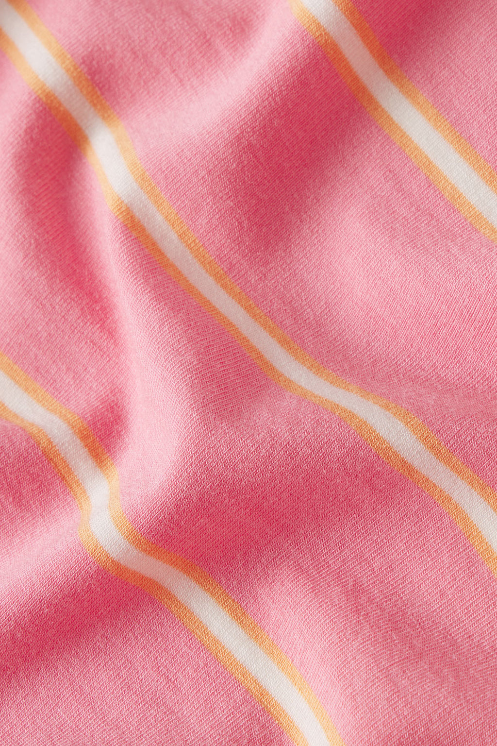Diagonal striped fabric in pink, coral, white, and gold colors on knit material.