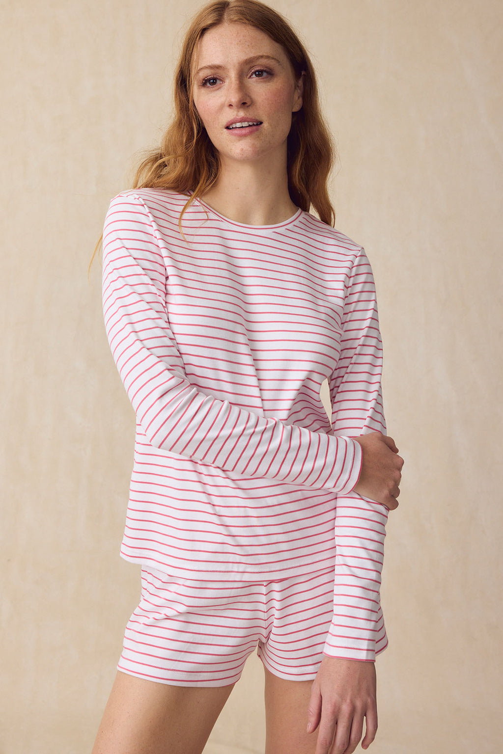 A woman wearing the Pima Crew Long Sleeve Bundle in Winterberry Rowing Stripe poses against a plain beige background, smiling slightly.