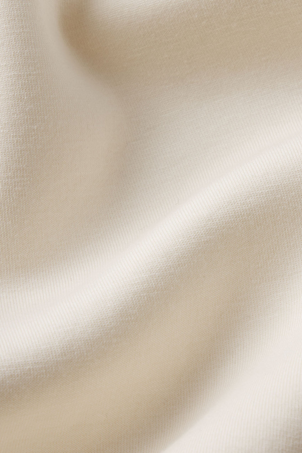 A close-up of the soft, cream-colored spacer knit fabric in the Dash Short Set in Parchment shows gentle folds, smooth texture, and a fine weave—ideal for a stylish and comfortable outfit.