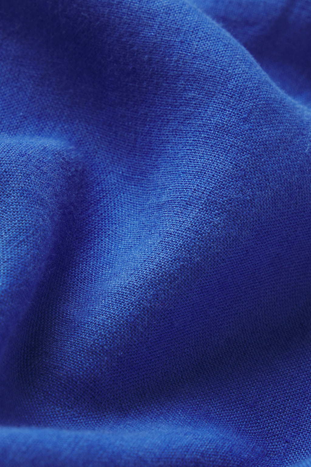 A close-up of the vibrant blue Cruise Short Set in Lapis shows textured fabric and soft folds, with gentle shadows and highlights enhancing its linen-like appearance.