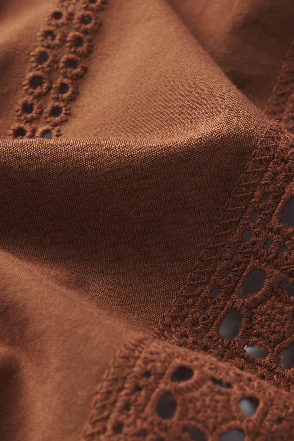 Close-up of the Cafe Shorts Set in Cinnamon Eyelet: made of 100% cotton brown fabric featuring intricate eyelet crochet lace and textured embroidery for a soft feel and decorative, delicate details.