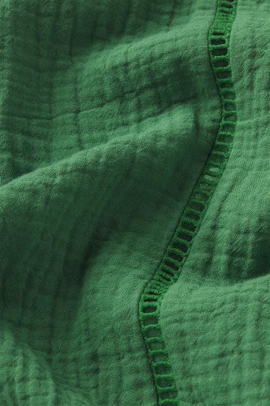 Close-up of the Cabana Skirt Set in Palm, showing emerald green cotton gauze fabric with a textured weave, visible vertical stitched seam, and a slightly crinkled finish.