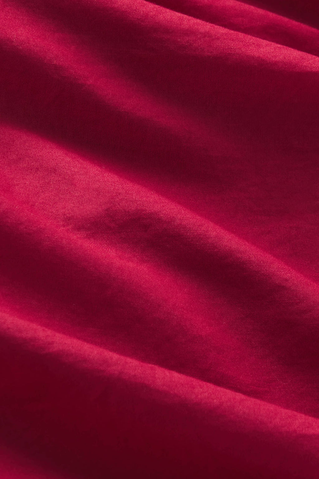 Burgundy ribbed knit fabric with draped folds and texture detail.