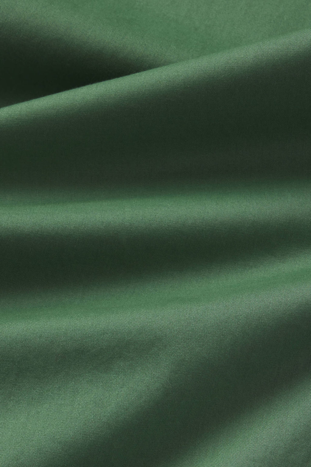 Close-up of sage green ribbed fabric with diagonal folds and shadow texture detail.