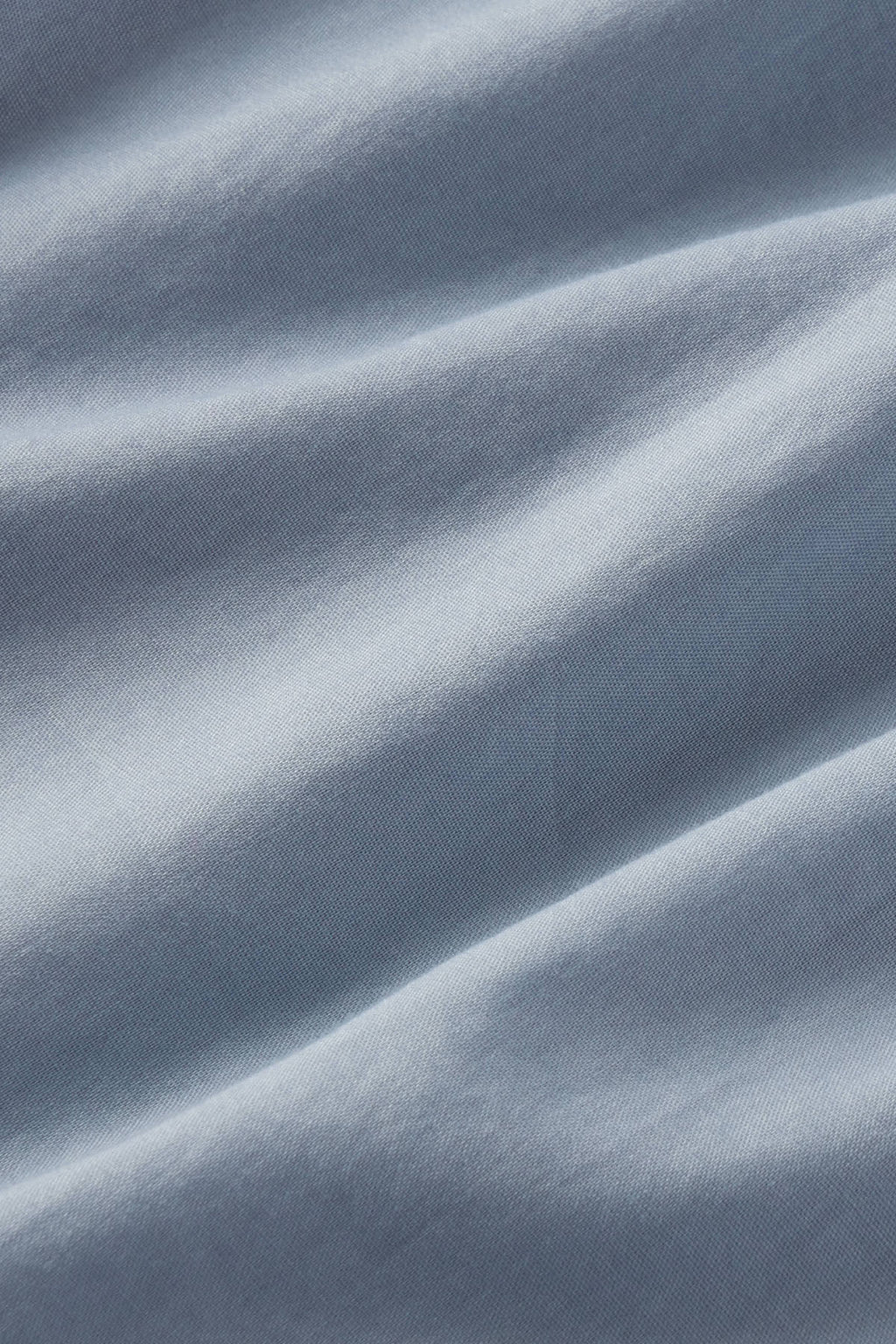 Dusty blue textured fabric with diagonal folds and light reflection showing the material