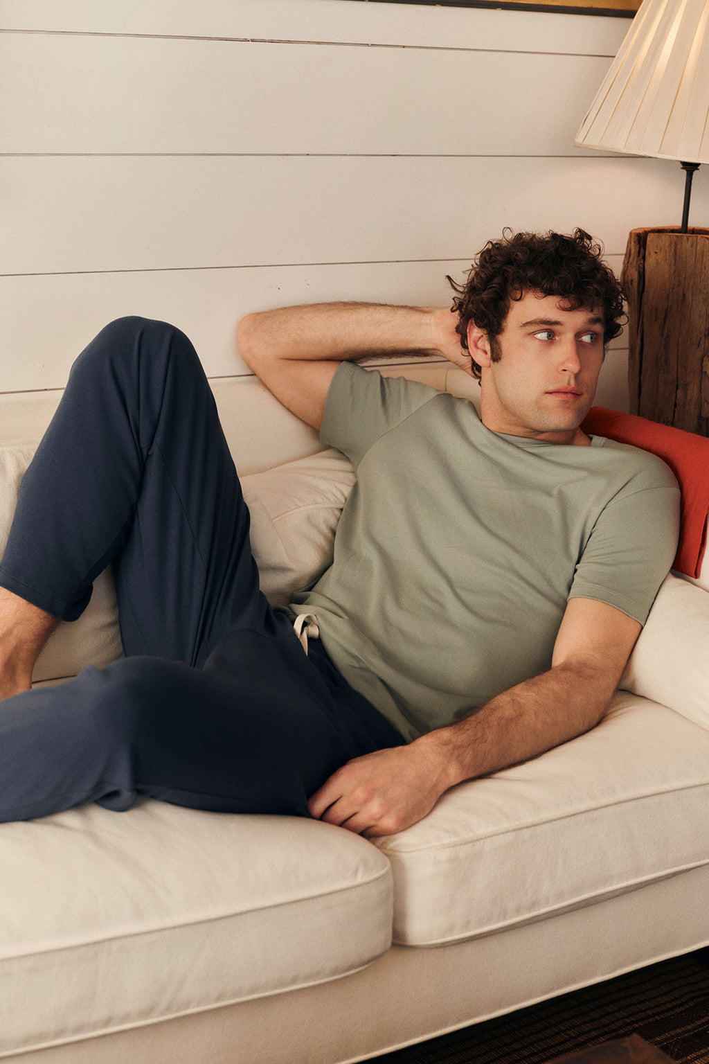 Lounging on a cream sofa, a man in the Men