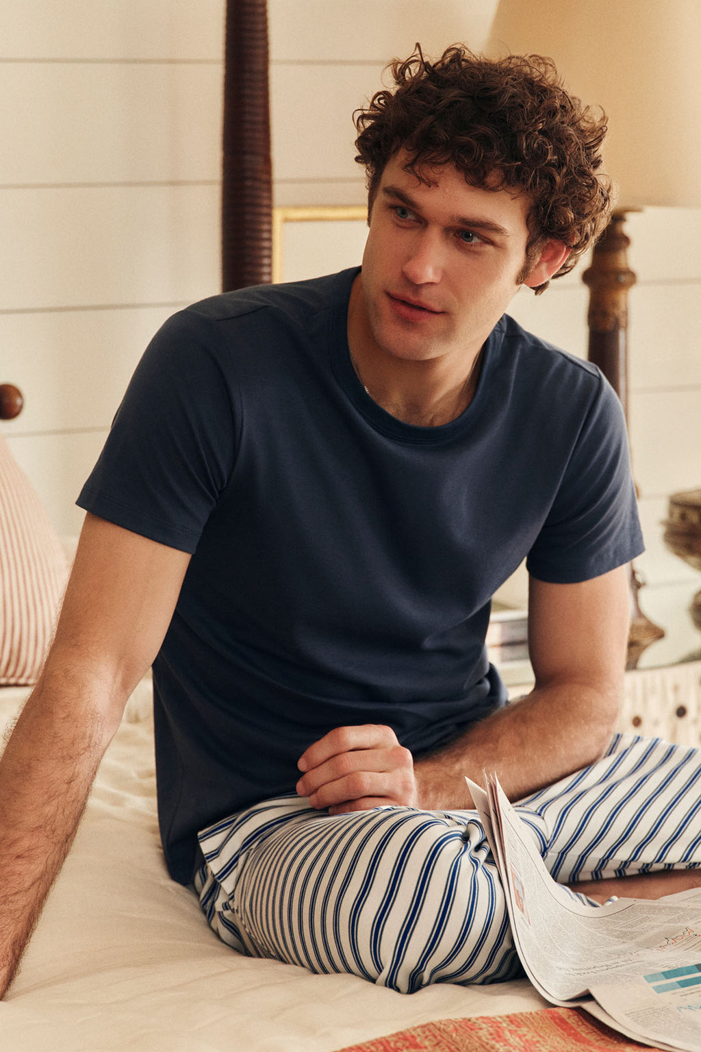 A young man sits on a bed wearing the Men