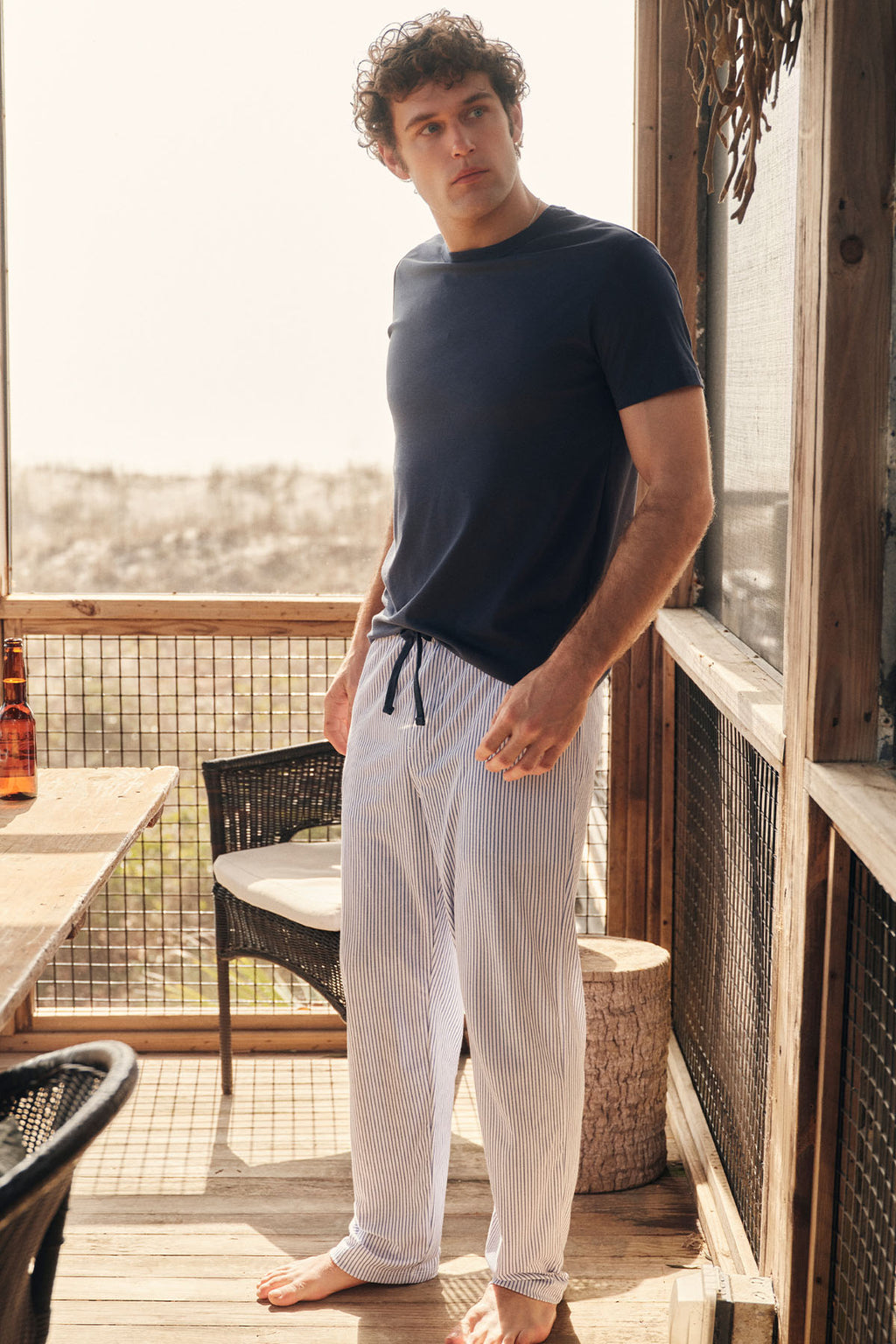 Man wearing navy short-sleeve shirt and striped long pants with compass pattern design.