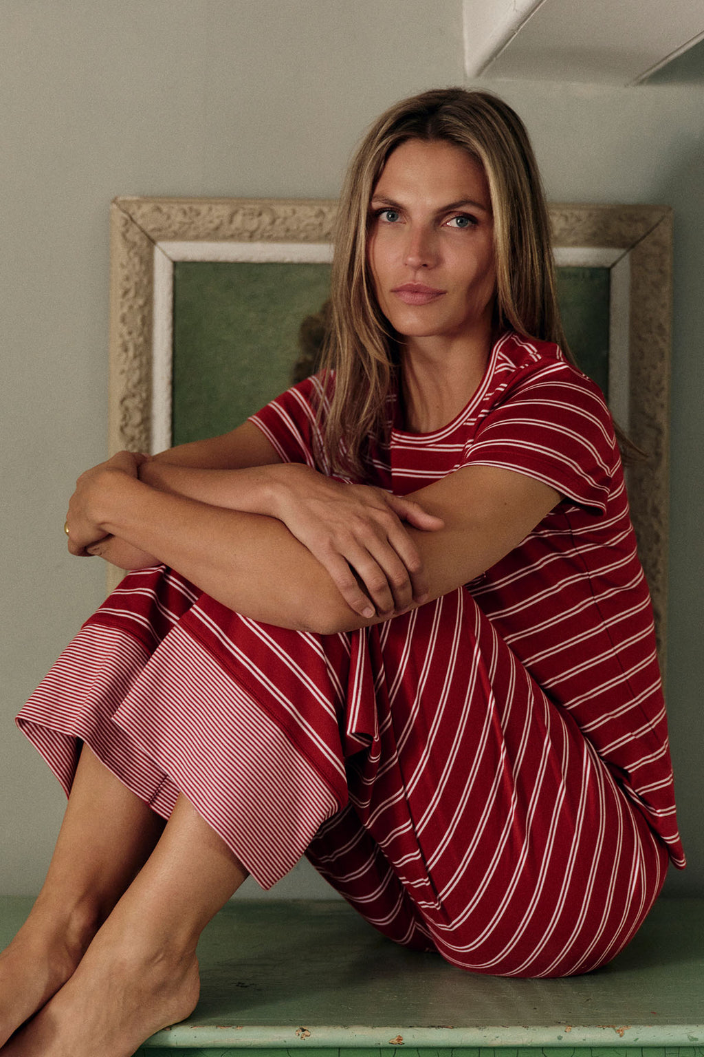 Woman wearing garnet and white striped crew neck pajama set with short sleeves and wide leg pants.
