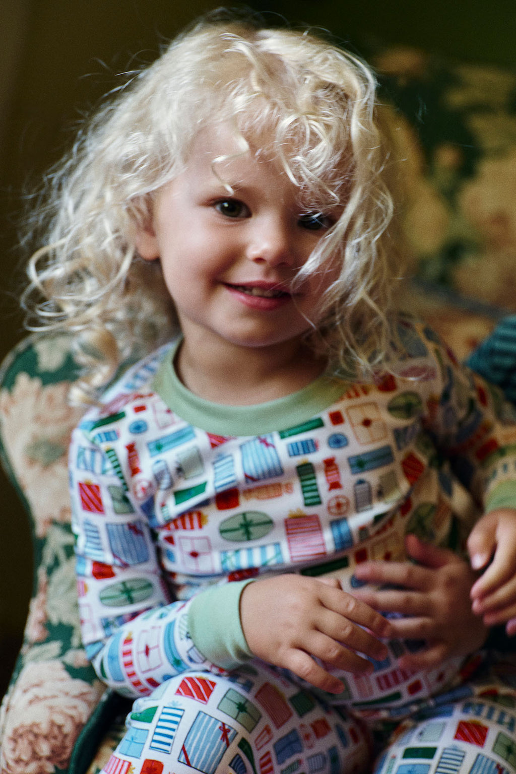 Young child wearing long-sleeve pajama set with multicolored geometric print on cream background.