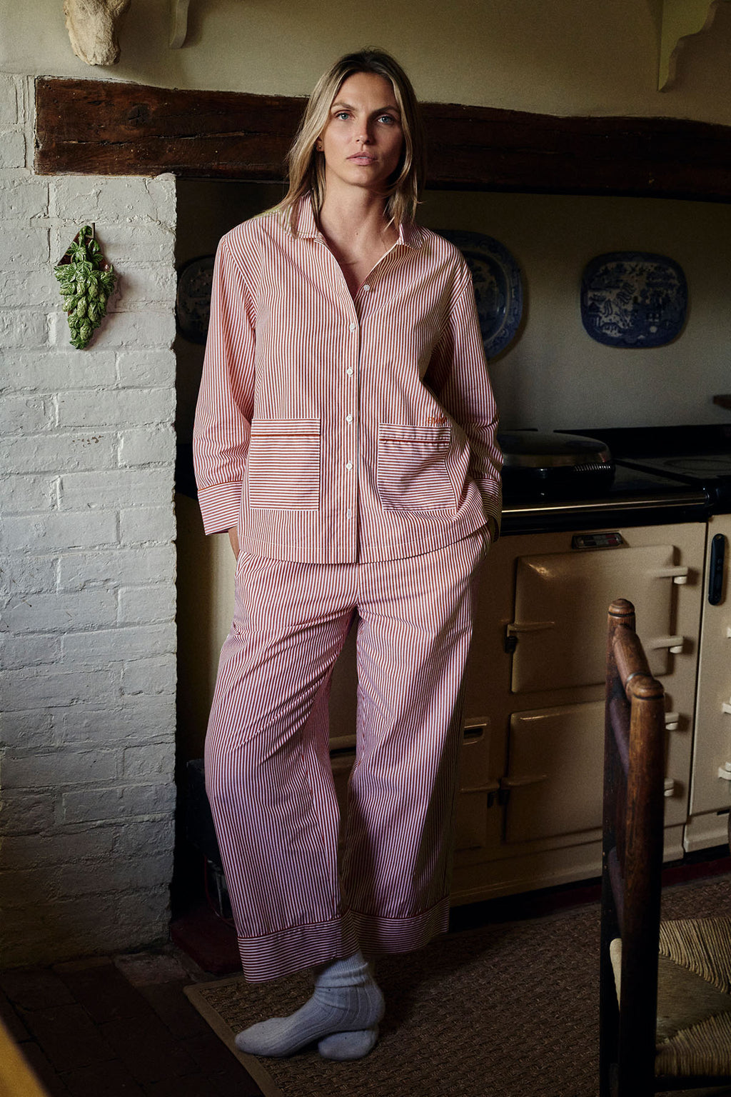 Woman wearing red and white striped long-sleeved button-up shirt and matching long pants with piped trim.