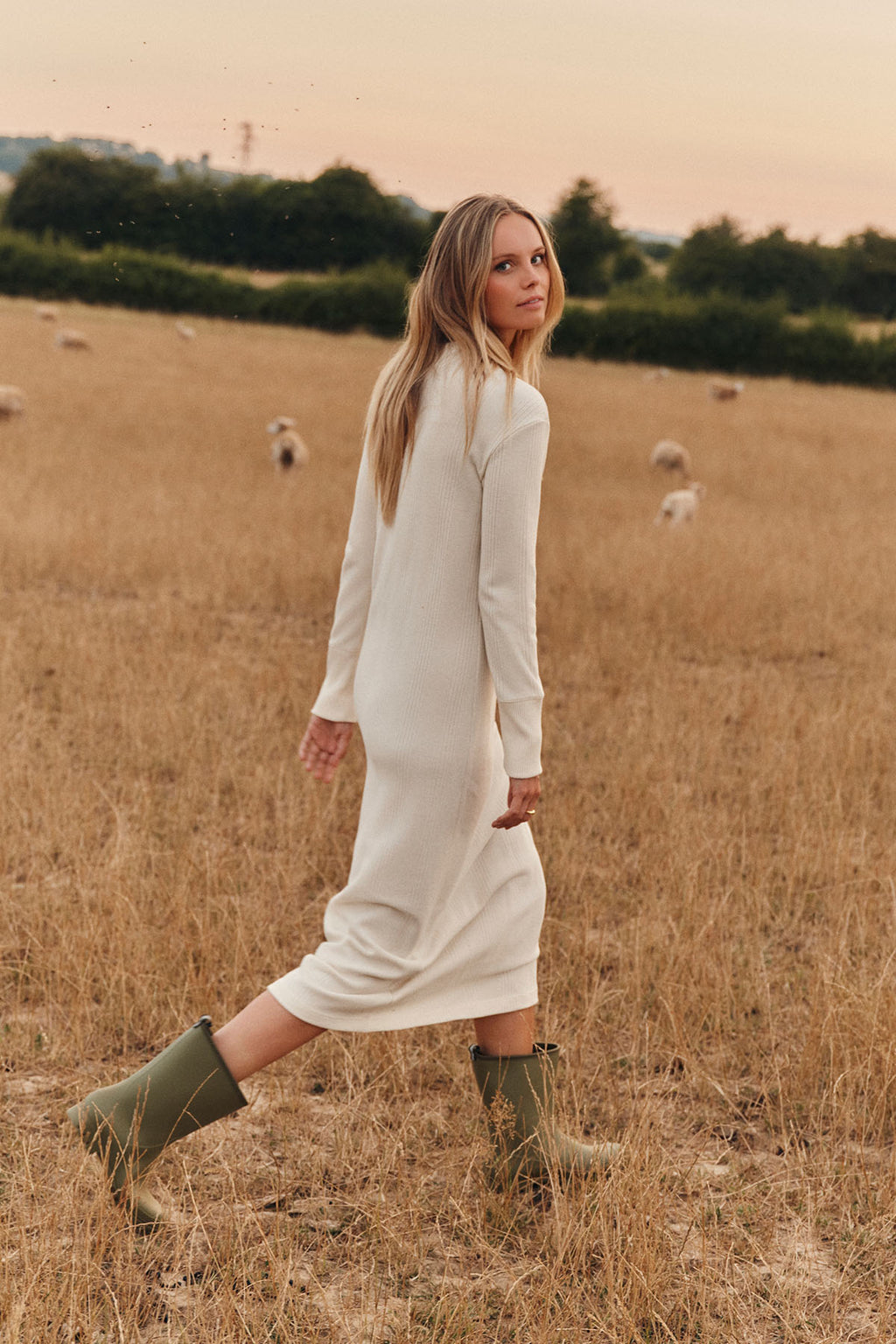 Ivory waffle-textured midi dress with long sleeves on model in rural field setting.