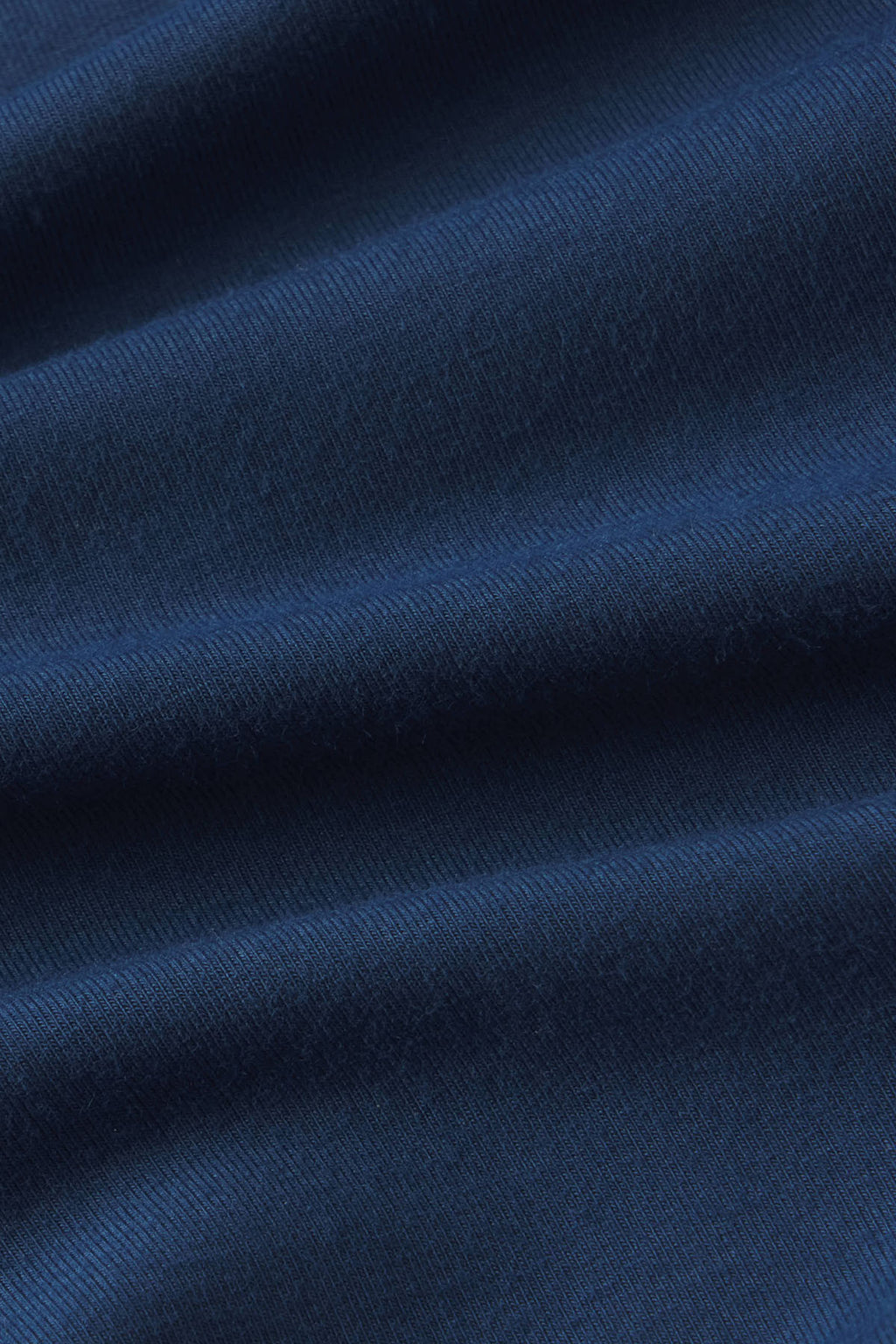 Close-up of navy blue textured fabric with diagonal folds showing woven pattern detail.