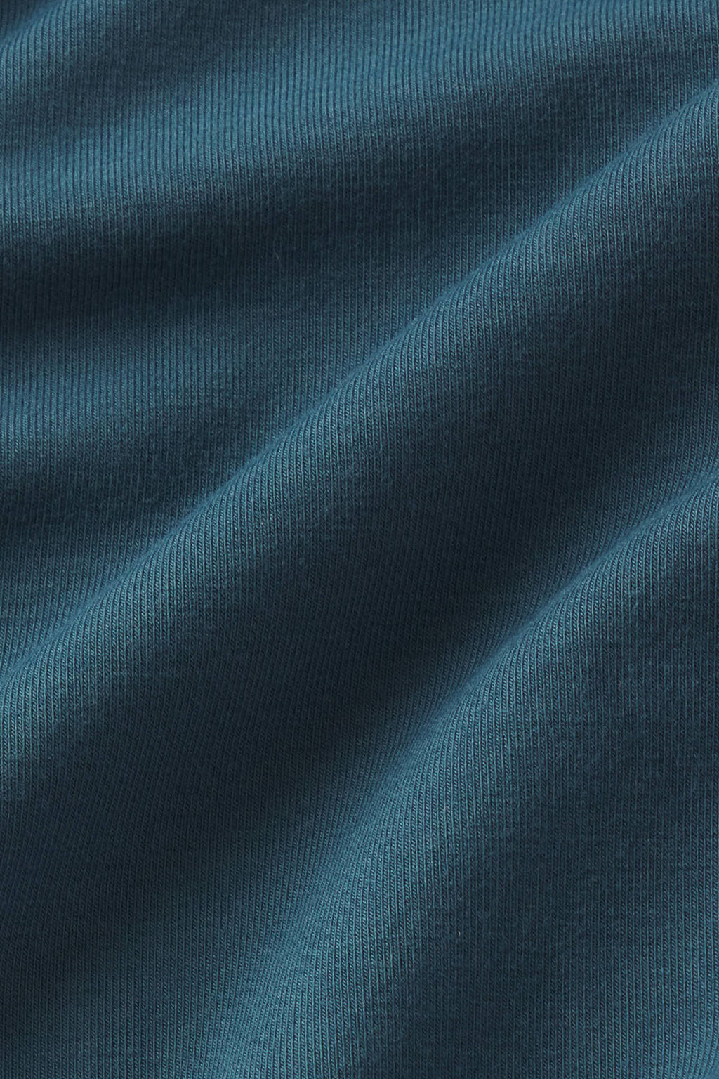 Close-up of teal-blue ribbed fabric with diagonal folds and texture detail.