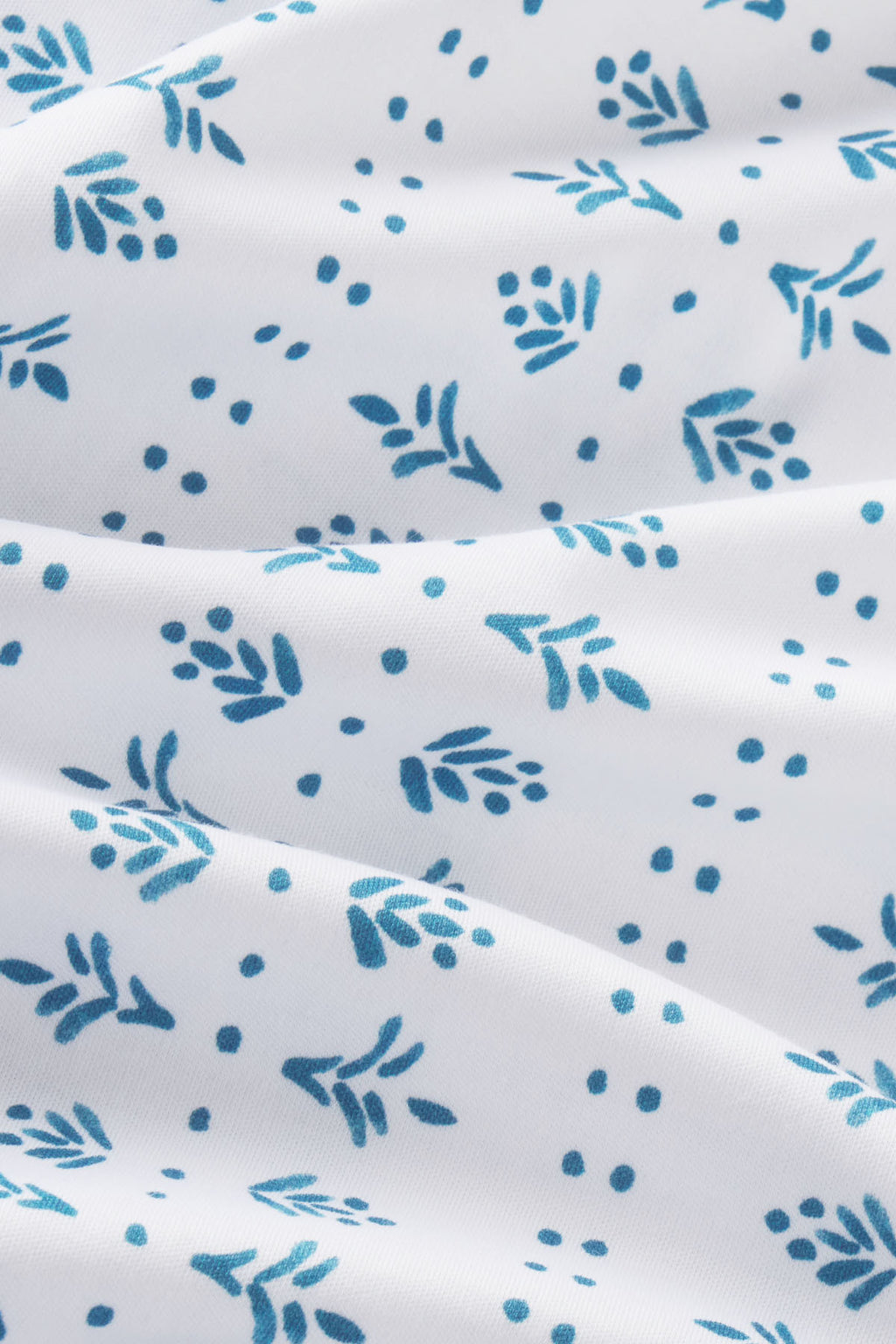White Pima cotton fabric with teal leaf and dot pattern.