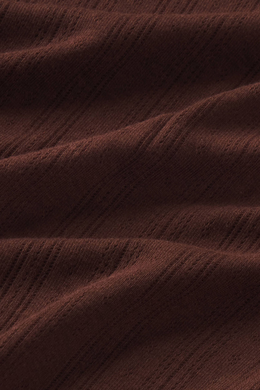 Cocoa-brown pointelle knit fabric with vertical ribbed texture and subtle gathering folds.