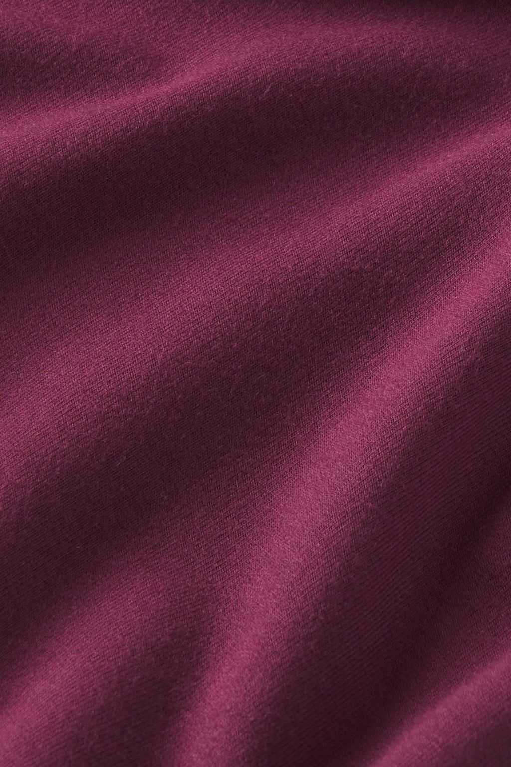 Fig-colored knit fabric with textured surface and diagonal folds.