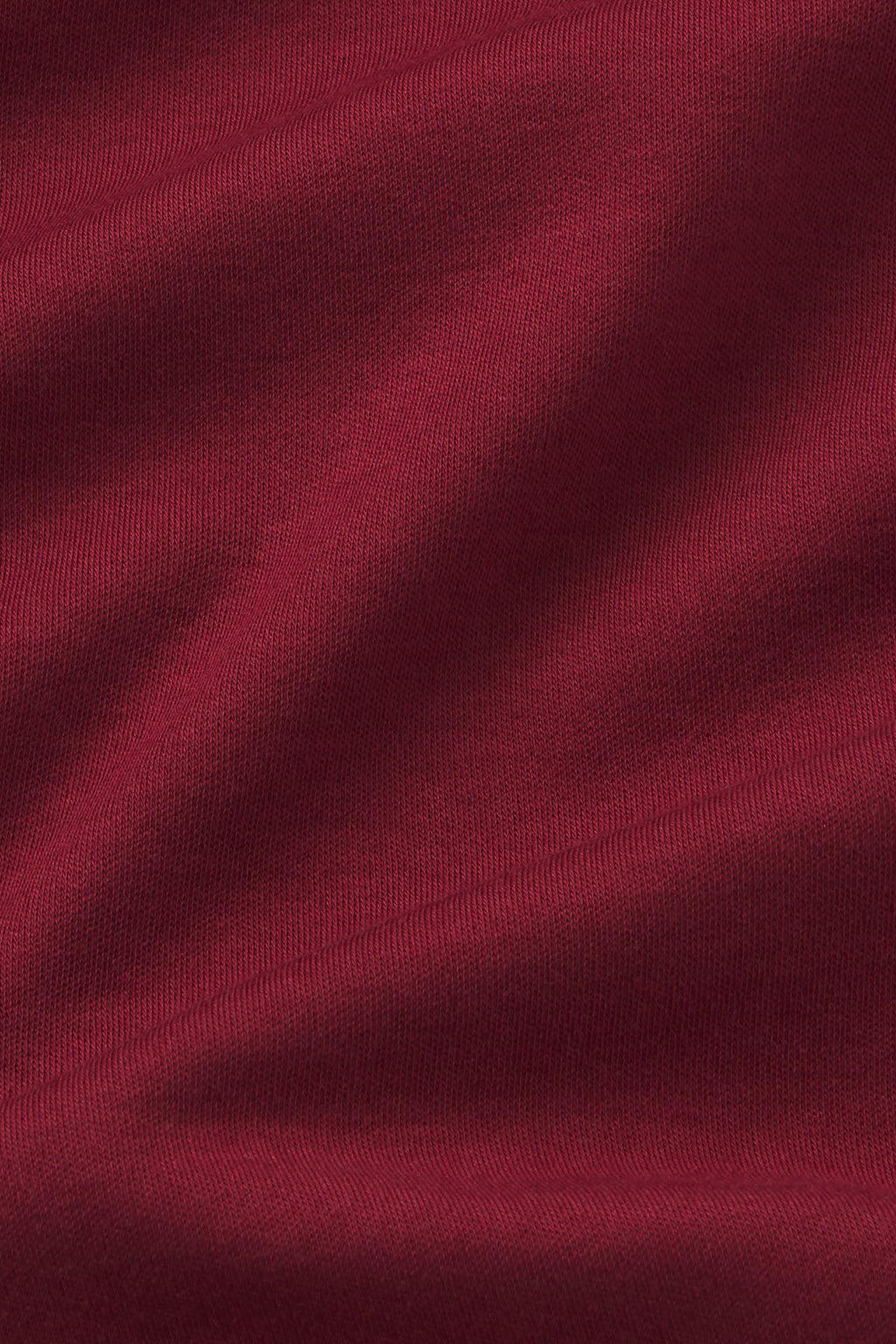 Deep burgundy ribbed knit fabric with wavy texture and natural wrinkles.