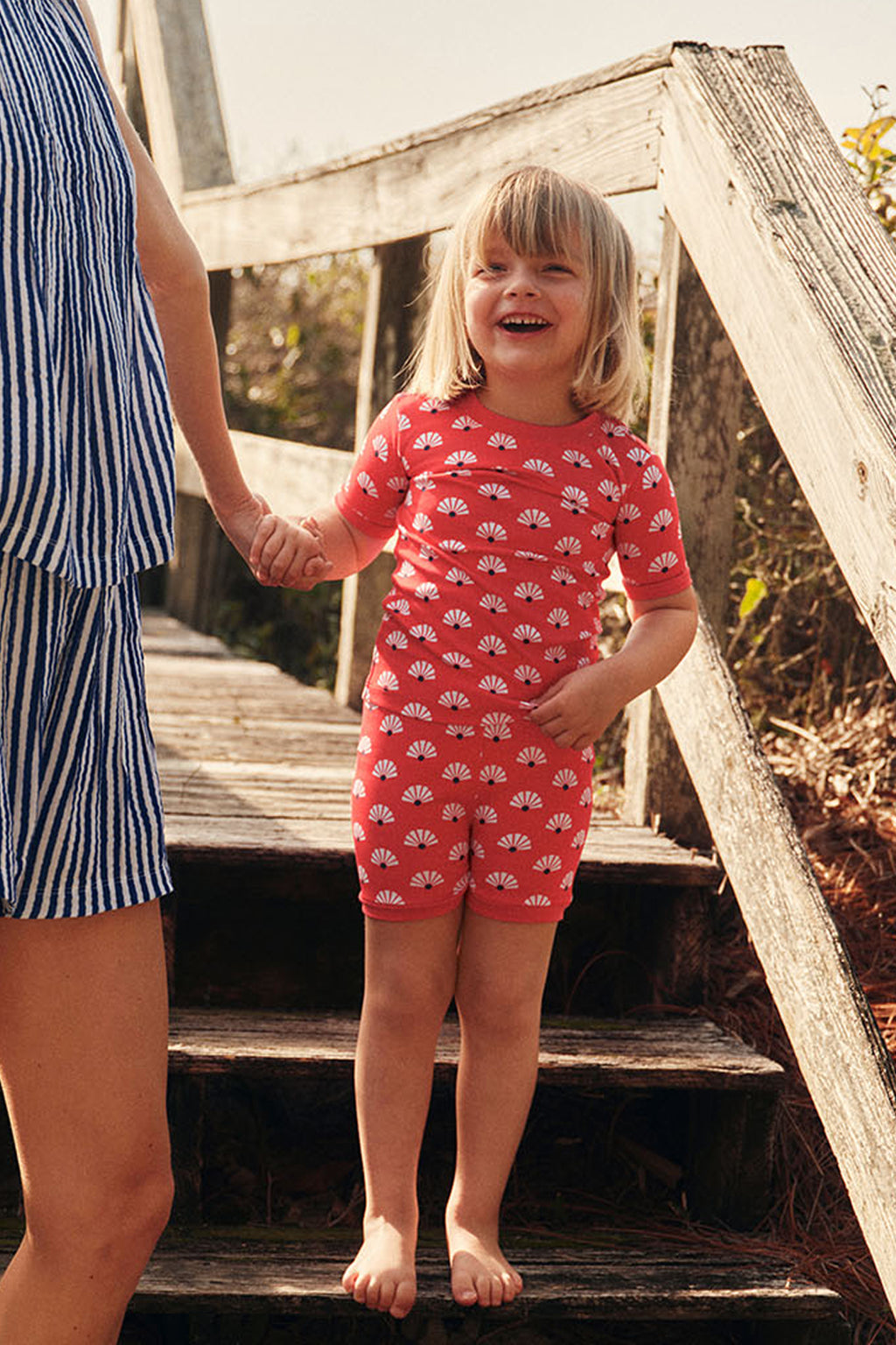 Young child wearing red shorts set with white scallop shell pattern and matching short-sleeve top.