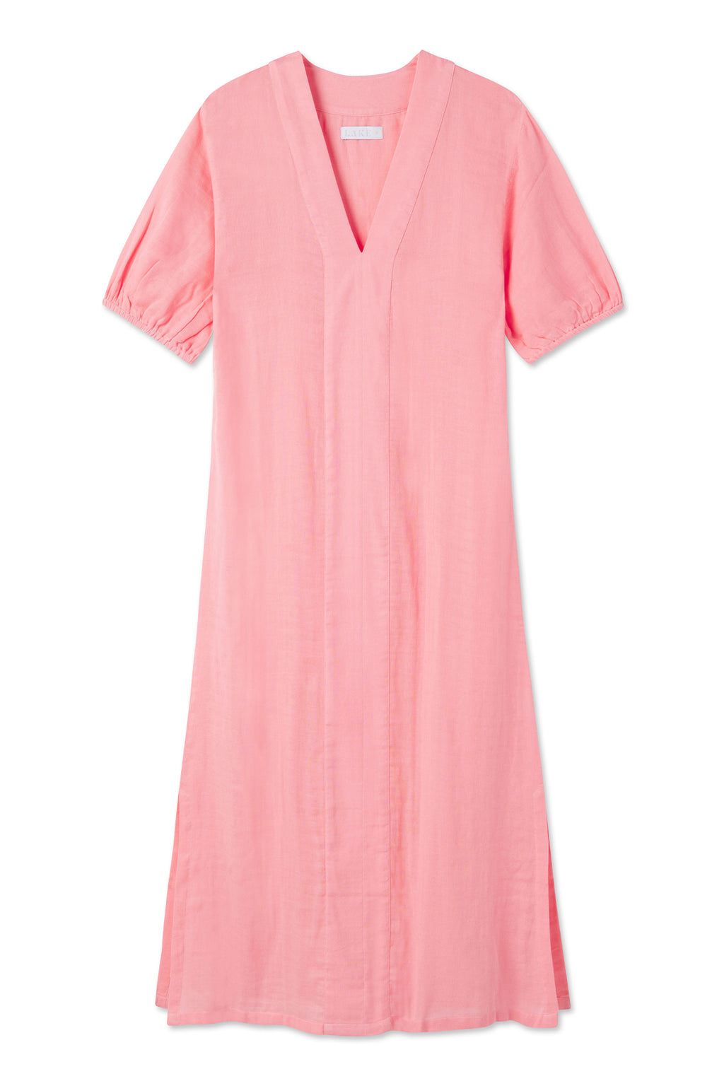 The Gauze Caftan in Coral is a light pink, knee-length dress with short puff sleeves, a V-neckline, and subtle front seam detailing. Made from 100% cotton, it offers a loose, relaxed fit for comfortable wear.